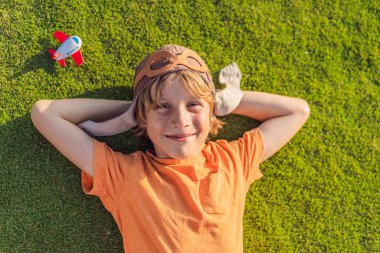 Pilot şapkası takan bir çocuk oyuncak bir uçakla çimlerde koşuyor, maceralar hayal ediyor. Çocukluk, hayal gücü ve özgürlük kavramı..