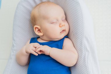 Tombul 3 aylık bebek evdeki rahat bir bebek yuvasında huzur içinde uyuyor. Sıcak ve besleyici bir ortamda bebek konforu, güvenlik ve erken gelişim kavramı.