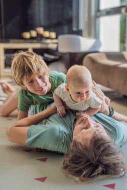 Baba, oğul ve yeni doğan bebek sıcak bir kreşte yerde yatıyorlar ve yeni aile üyelerinin gelişini kutluyorlar. Ebeveynlik, bağlılık ve aile sevgisi kavramı.
