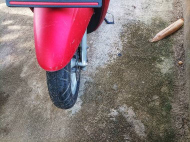 Kırmızı motosiklet çamurluğu park halindeyken görülmüş.