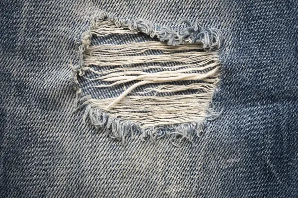 Kot pantolonu yırtılmış. Kot pantolon moda geçmişi. Mavi kot kumaş dokusu arka planı. Denim kot kumaşı. Tasarım için Denim arkaplan dokusu.