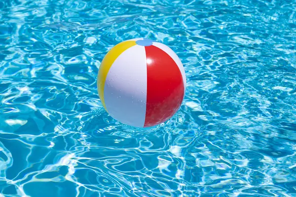 Yüzme havuzunda yüzen plaj topu. Yaz tatili ilanı. Mesaj için yer var. Yüzme havuzunda renkli plaj topu