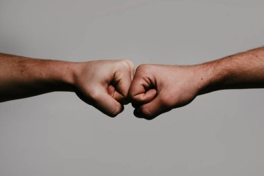Yumruk Bump. İki yumruk. Yüzleşme kavramı, rekabet. Saygı gösterme ya da onaylama hareketi. Takım çalışması ve arkadaşlık. Ortaklık kavramı. Adam yumruk tokuşturuyor. Yumruk tokuşturma