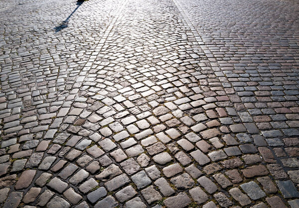 Pavement road. Background of bricks road. Stone cladding pavement. Brick surface background. Rough brick road. Cobblestone pavement background. Textured background. Sidewalk. Old cobblestone road