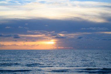 Manzaralı sahil manzarası. Okyanus dalgaları arka planı. Bulutlarla kaplı denizde gün doğumu