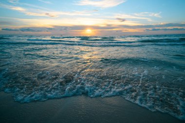 Manzaralı sahil manzarası. Okyanus dalgaları arka planı. Bulutlarla kaplı denizde gün doğumu