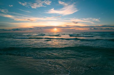 Manzaralı sahil manzarası. Okyanus dalgaları arka planı. Bulutlarla kaplı denizde gün doğumu