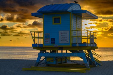 Miami Beach Florida, ABD 'nin ünlü tropikal seyahat yeri. Okyanus ve mavi gökyüzü olan bir yaz plajındaki cankurtaran evi. Günbatımı arka planı. Denizin üzerinde güneş. Okyanus dalgaları arka planı. Gün batımı ya da gün doğumu