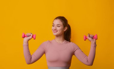 Spor. Fit Kız dambılları kaldırıyor. Ahmak. Dambılı kadın. Spor giyim sektöründe bir kadın. Halterleri kaldıran formda bir kadın. Fitness modeli dambılla pompalanıyor. Spor.