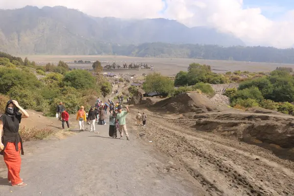 İnsanlar arka planda dağlarda yürüyorlar.