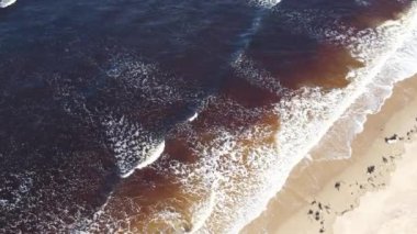 İskoçya 'da sahile vuran dalgalar doğrudan yukarıdan çekildi. Su yakındaki bir nehirdeki turba yüzünden kahverengidir..