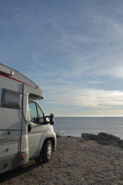 Okyanus kıyısındaki sahilde park etmiş bir karavan.