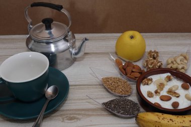 Kahvaltı, kahve, süt, tahıl ve fındık beyaz bir masada..