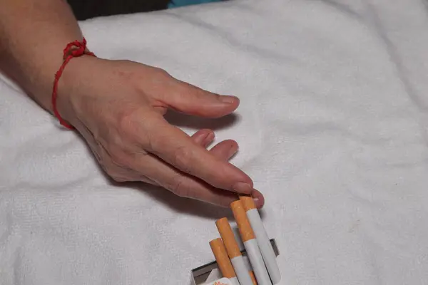 Adamın elinde kırmızı bir halka ve boş beyaz bir sigara vardı.