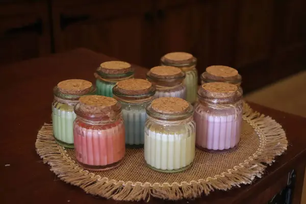 Ahşap masada farklı renkte kavanozlar olan cam kavanozlar.