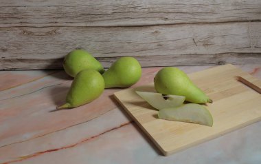 Tahta arka plandaki kesme tahtasındaki taze armutların yakın plan çekimi.