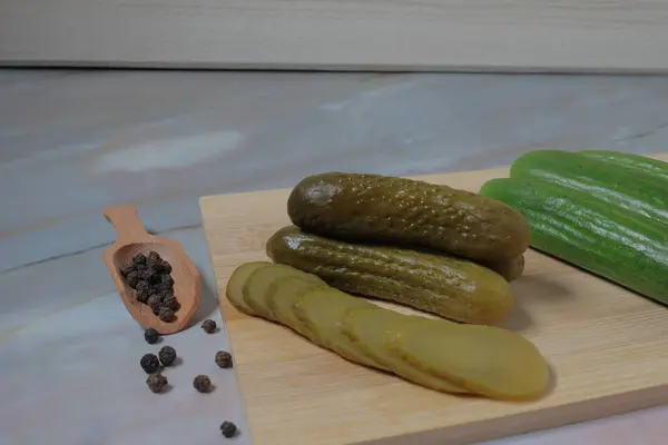 Beyaz bir masa örtüsüyle ahşap bir yüzey üzerinde salatalık ve baharatların yüksek açılı görüntüsü.