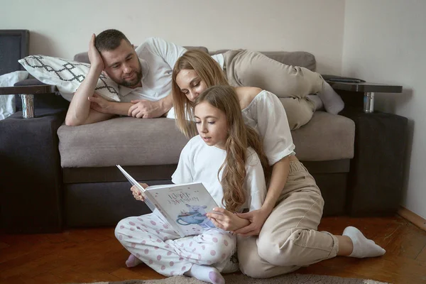 Parents read a book with their daughter