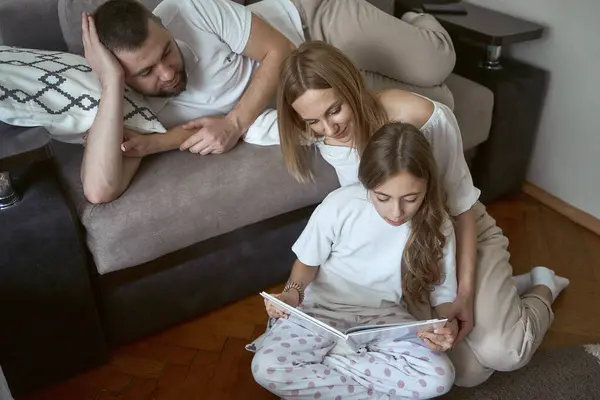 Parents read a book with their daughter