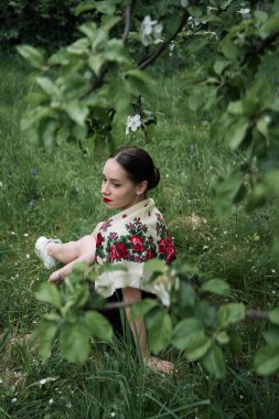 Çiçek açan elma ağaçlarının yanında eşarplı Slav kız.