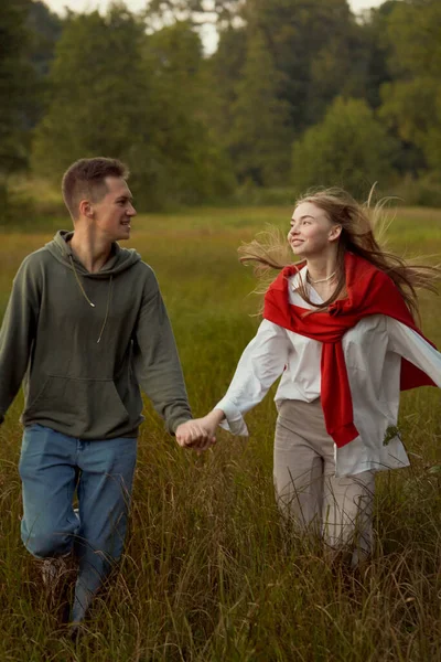 young teen couple run and play in field