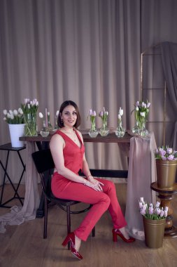          Kırmızı elbiseli bir kadın lalelerle çevrili.                      