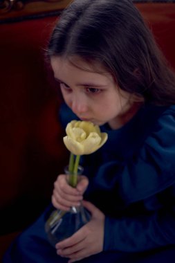            Üzgün kız kanepede laleyle oturuyor.                    