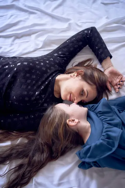 mother and daughter are lying on the bed