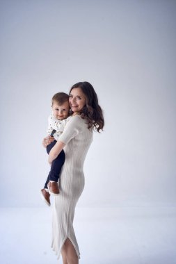              Güzel anne, minimalist bir stüdyoda oğlunu kollarına alıyor.                  