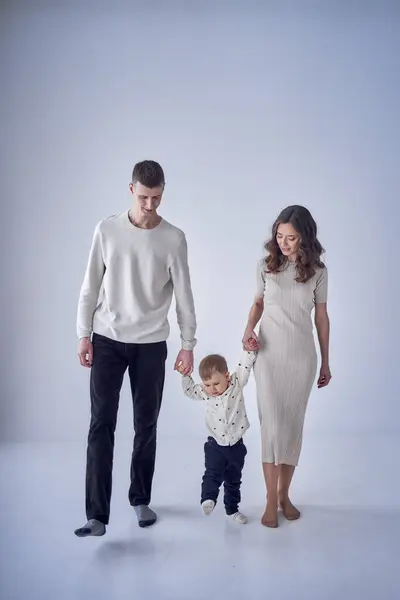 a minimalist portrait of a mother, father and their two-year-old son on a white background