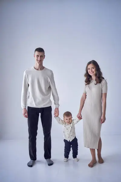 a minimalist portrait of a mother, father and their two-year-old son on a white background