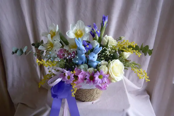 Easter floral arrangement with two blue Easter bunnies    in a wicker basket