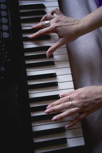 60-year-old mother and a 40-year-old daughter play the keyboard together on the bed at home