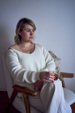 Orta boy bir kadın koltukta oturup kitap okuyor ve viski içiyor. Yanında da hediye çeki var.