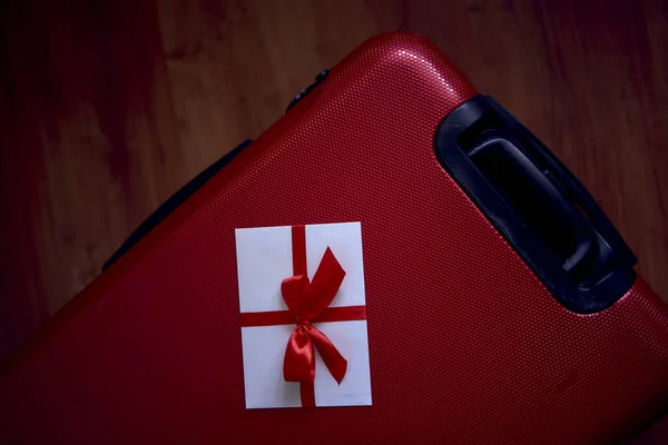 gift certificate in red and white colors on a red suitcase for travel