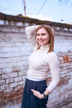         Güzel, orta yaşlı, süveter ve geniş paçalı pantolonlu bir kadın bahar günü dışarıda.                       