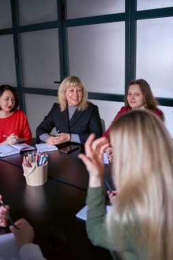         Ofisteki toplantıda gülümseyen orta yaşlı bir kadın.                      