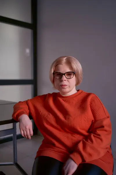 办公室里穿着橙色毛衣和皮裤的残疾妇女的肖像 — 图库照片