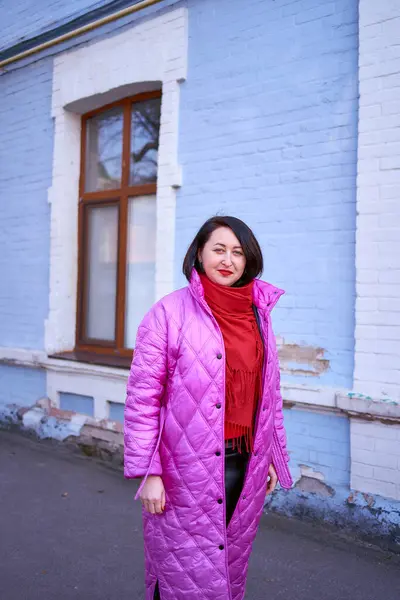 穿着亮丽的粉色 洋红色外套和红鞋子的中年妇女走在城市的街道上 — 图库照片