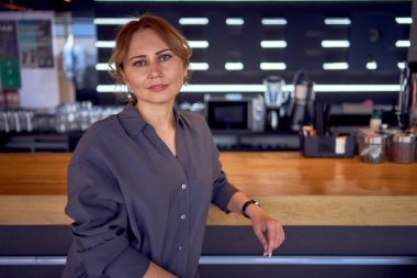 Tarafsız tasarlanmış, geniş paçalı pantolon ve ipek bluz giyen çekici, orta yaşlı bir kadın.                       