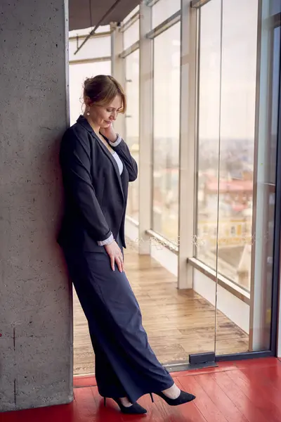 stock image am attractive middle age woman in jacket and white t-shirt posing in modern office with panoramic windows                     