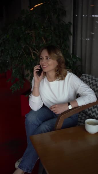 Kobieta Swetrze Dżinsach Rozmawia Przez Telefon Pięknej Kawiarni Zielenią Panelami — Wideo stockowe