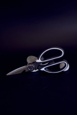 a   kitchen scissors with a jagged blade on a black background                     clipart