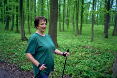 Yaşlı bir kadın İskandinavya 'da Bahar Ormanı' nda sopalarla yürüyor.