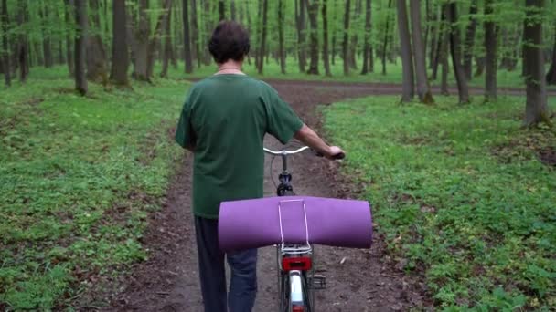 Egy Idős Sétál Tavaszi Erdőben Kerékpárral Jóga Szőnyeggel — Stock videók