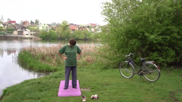 Nehir Kıyısında Egzersiz Yapan Yaşlı Bir Kadın Yanında Bir Bisiklet — Stok video