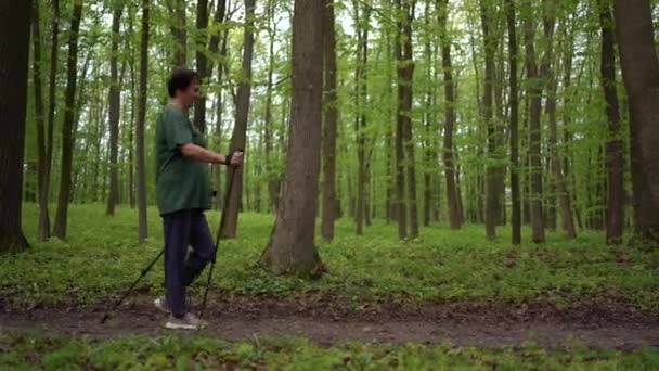 Μια Ηλικιωμένη Γυναίκα Ασχολείται Σκανδιναβικό Περπάτημα Μπαστούνια Στο Δάσος Άνοιξη — Αρχείο Βίντεο