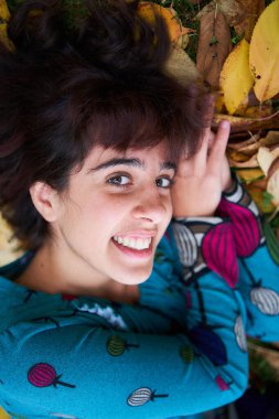  Sonbahar yapraklarıyla kaplı balonlu bir kız yerde yatıyor.