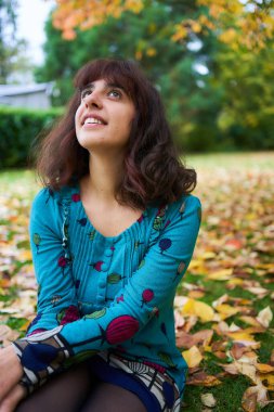  Sonbahar yapraklarıyla kaplı balonlu bir kız yerde yatıyor.