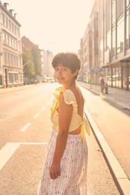 Kopenhag 'ın güneşli sokaklarında kısa saçlı, sarı elbiseli bir kız.